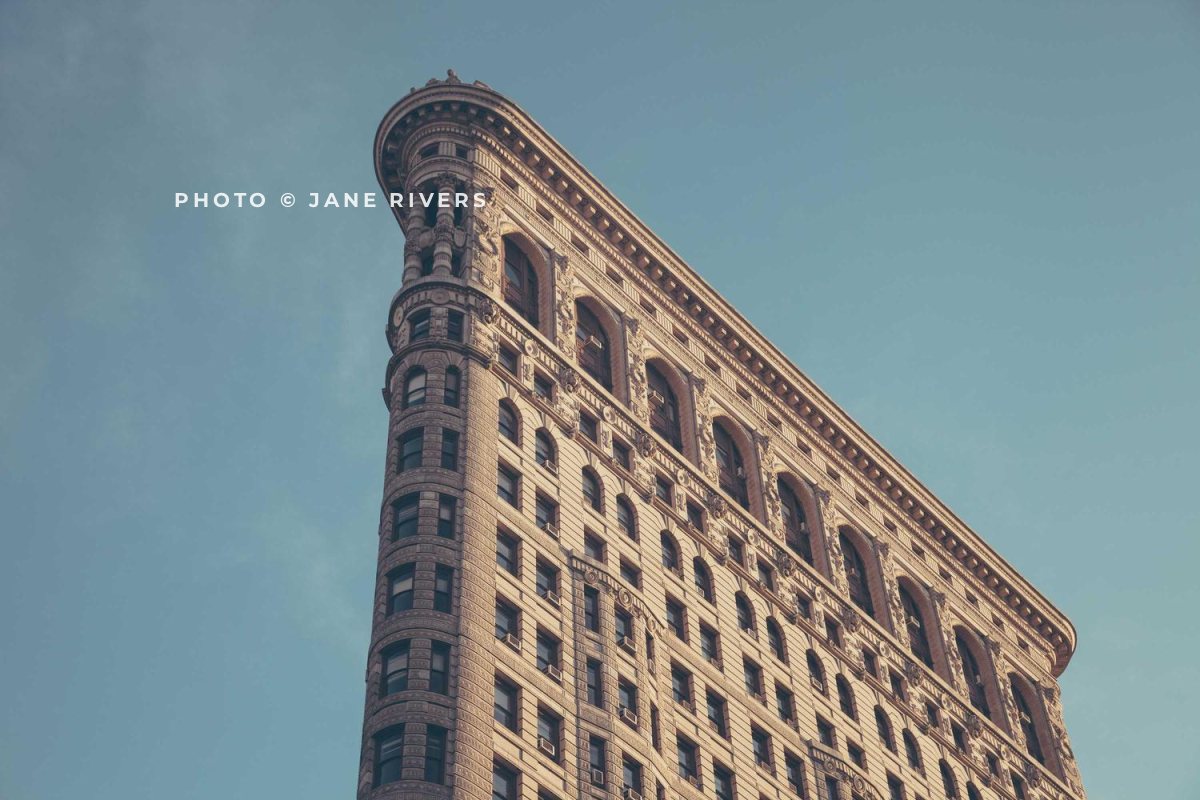 A narrow historic building against a plain sky with the credit in the open sky