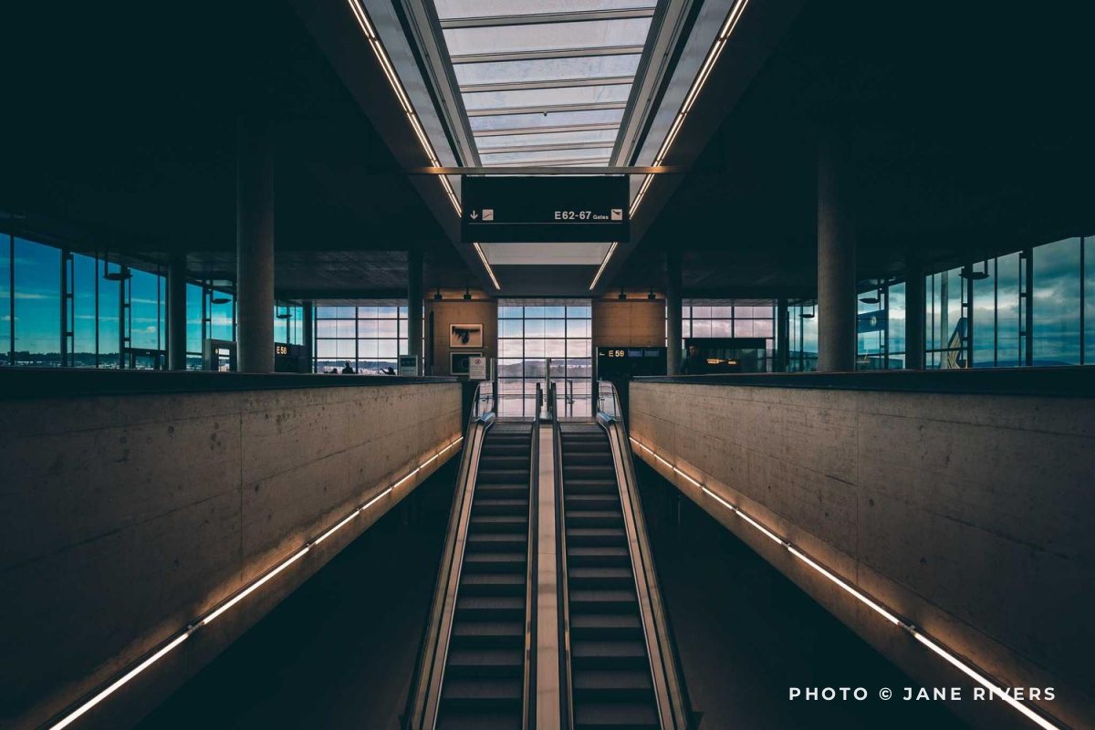 A symmetrical escalator corridor with the credit in the bottom right corner