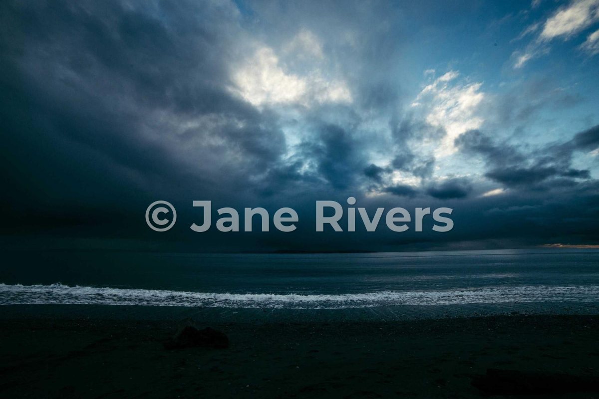 A stormy sea with a watermark across the middle, leaving the sky and the beach clear