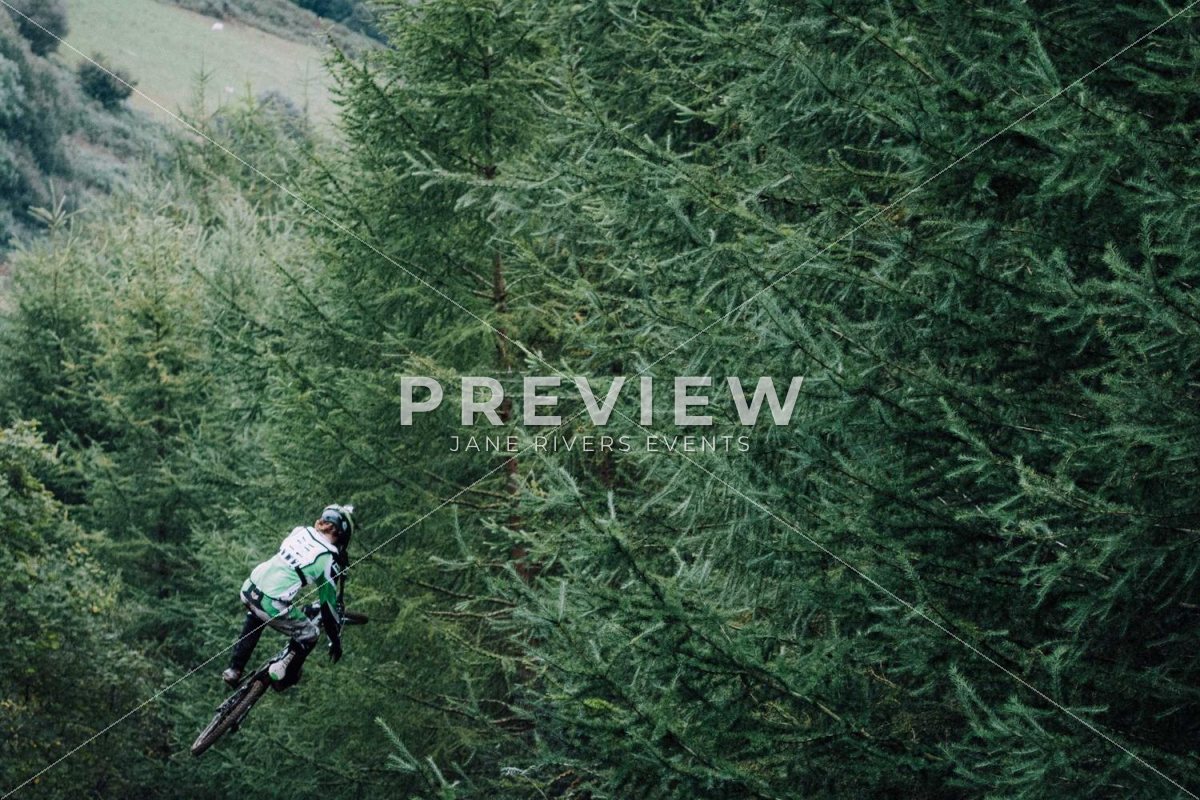 A mountain biker in a forest with a PREVIEW watermark and faint diagonal lines
