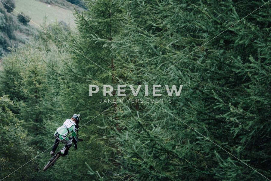 A mountain biker in a forest with a PREVIEW mark and diagonal lines