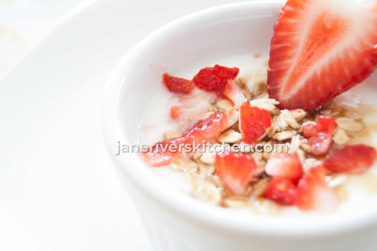 A bowl of yogurt with strawberries with a watermark across the fruit