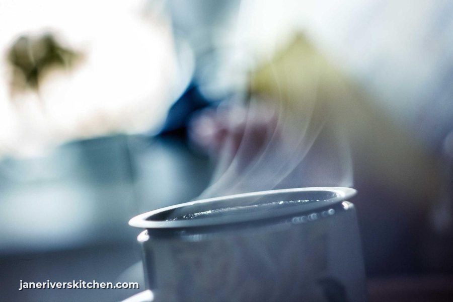 A steaming cup with a small white website watermark in the lower left