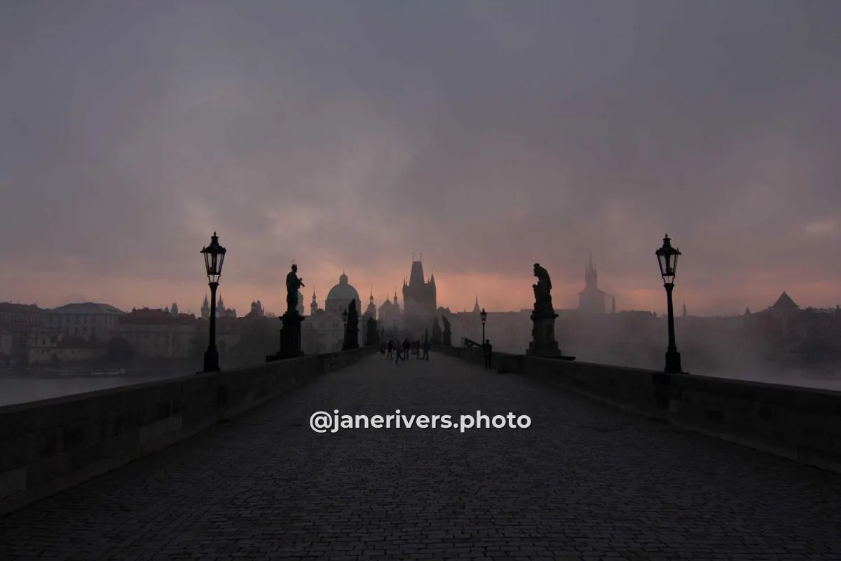 A misty bridge at dawn with @janerivers.photo written small in the lower third