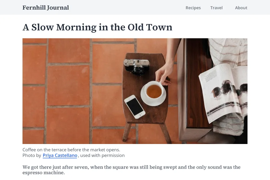 A simple blog article layout with a photo of coffee and a camera on a terrace, and a caption underneath reading Photo by Priya Castellano, used with permission, with the name as a link