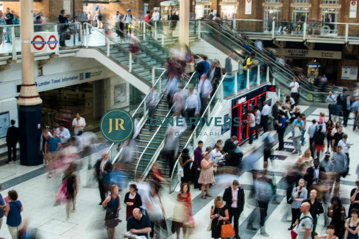 A busy train station with a dark teal logo and name that blend into the crowd