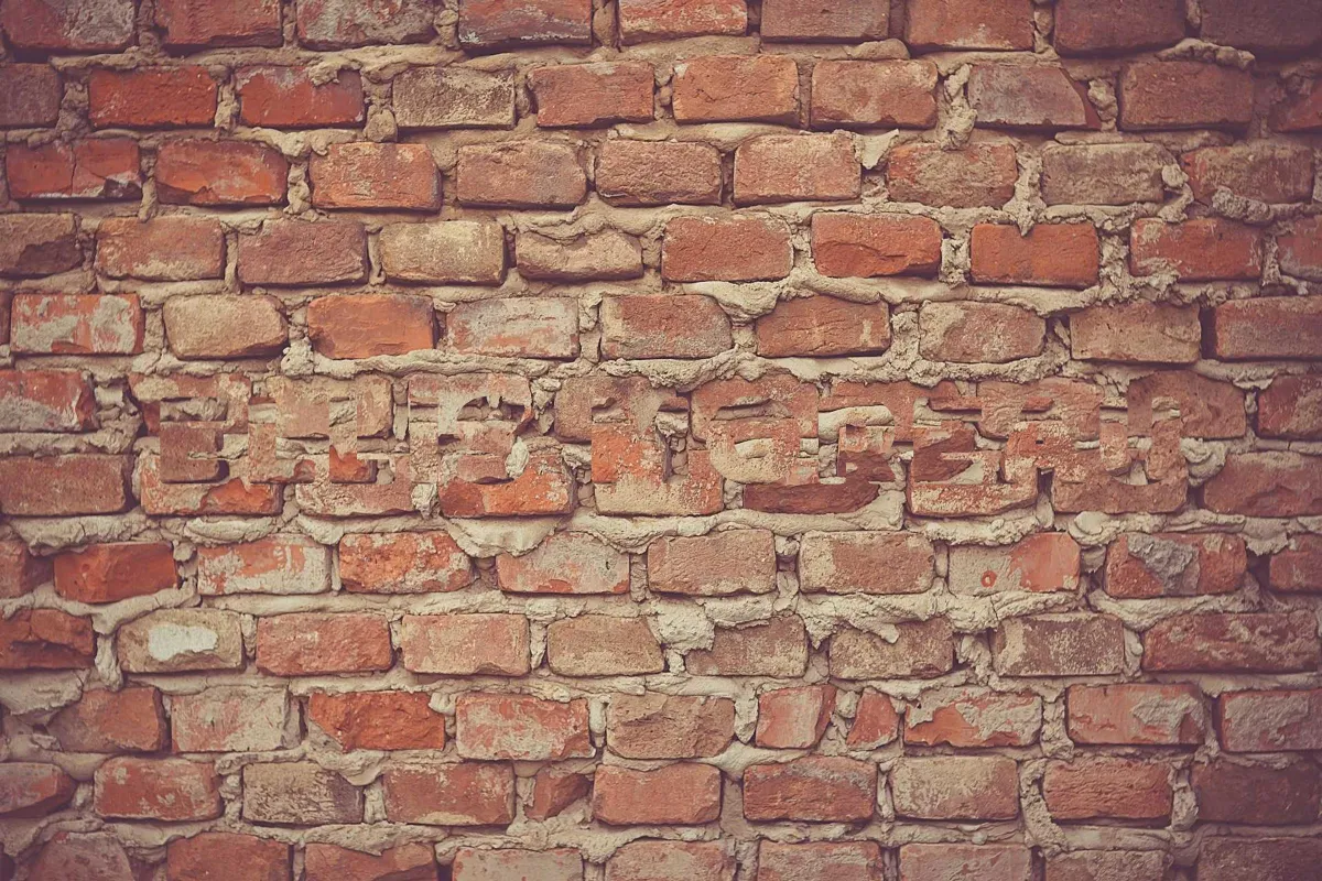 The same brick wall after a simulated careless clone, where the mortar lines break and shift inside the shapes of the letters, leaving the name faintly readable