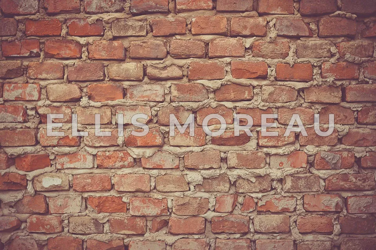 An old red brick wall with ELLIS MOREAU in large semi-transparent white capitals across the middle