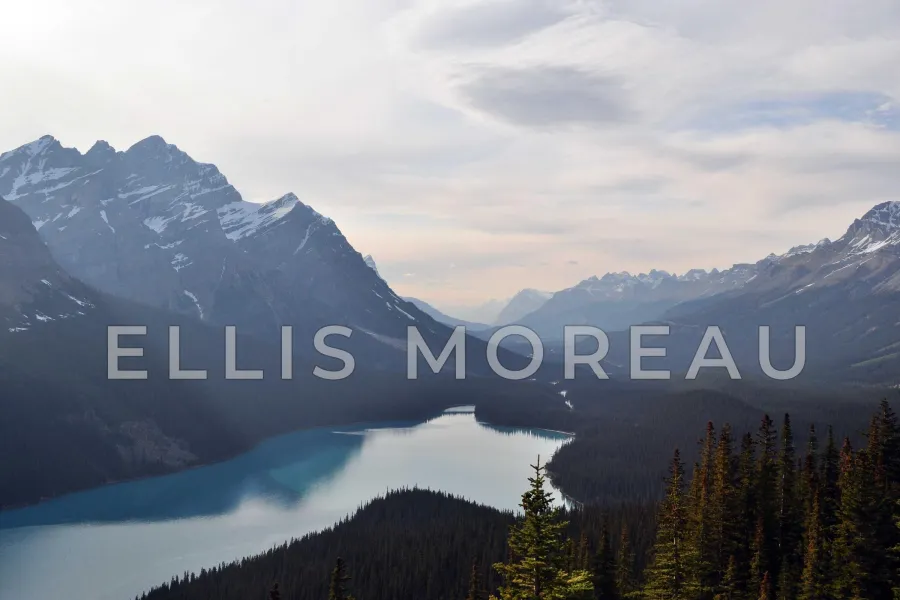 A turquoise mountain lake between forested slopes, with ELLIS MOREAU in large, widely spaced letters across the middle of the frame