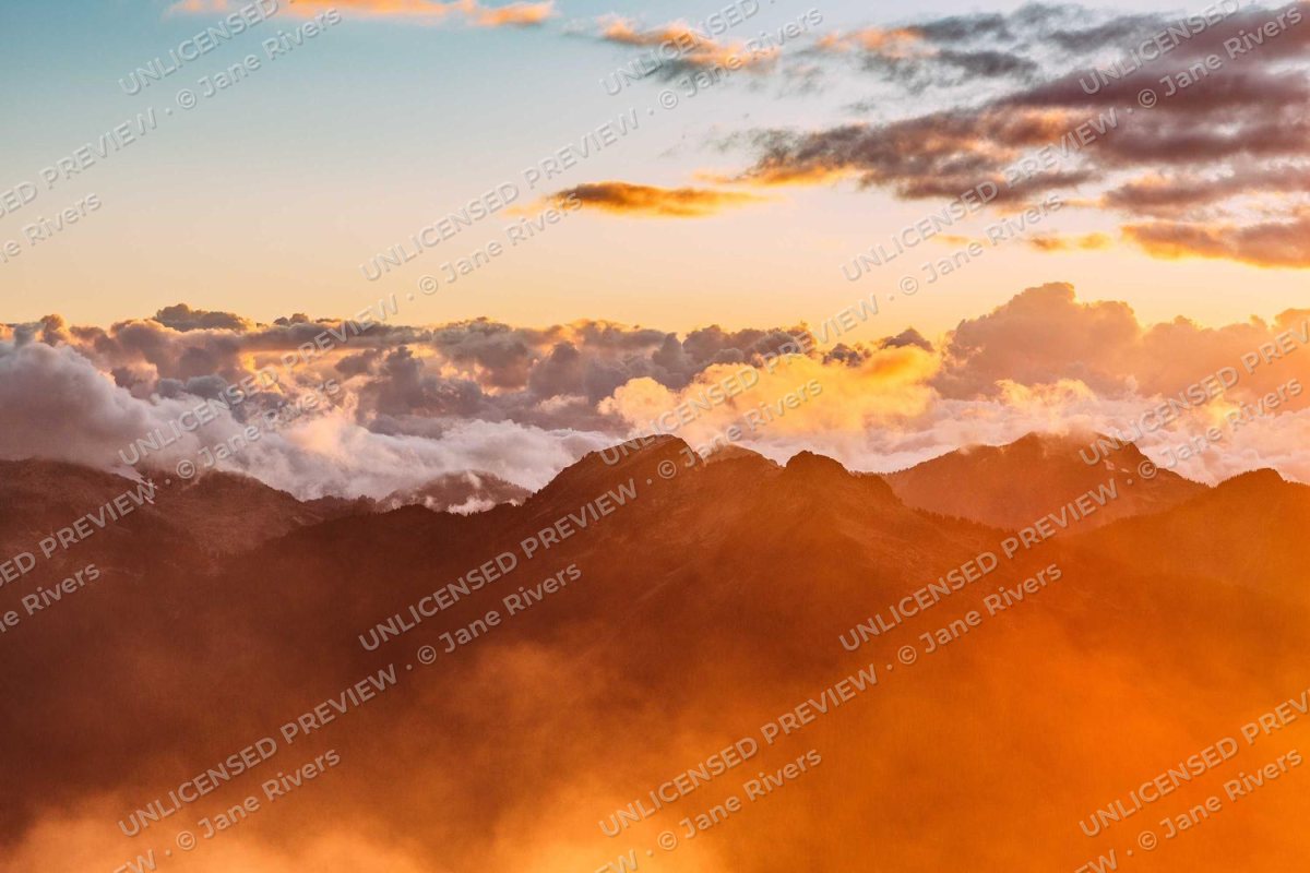A sunset over clouds and mountains with a faint tiled watermark reading UNLICENSED PREVIEW