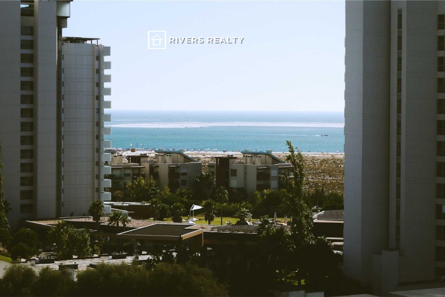 Apartment buildings with a sea view and a small agency logo in the sky