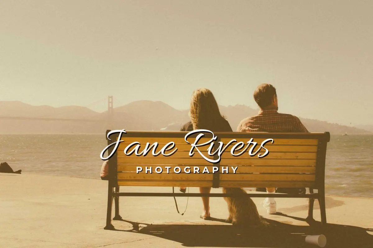 A couple on a bench by the sea with a handwritten Jane Rivers signature and the word Photography below it