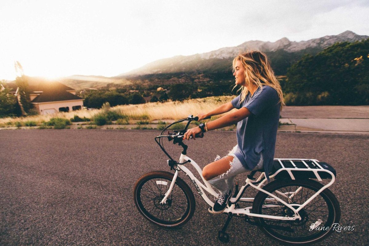 A woman on an electric bike with a tiny signature in the bottom corner that is hard to make out
