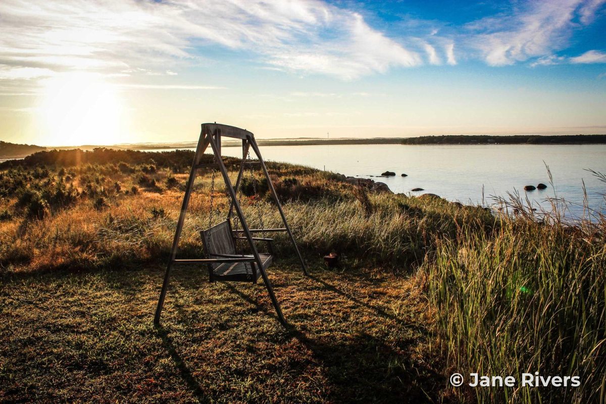 The full, sharp original photo of a swing on a grassy shore at sunrise, with a copyright watermark