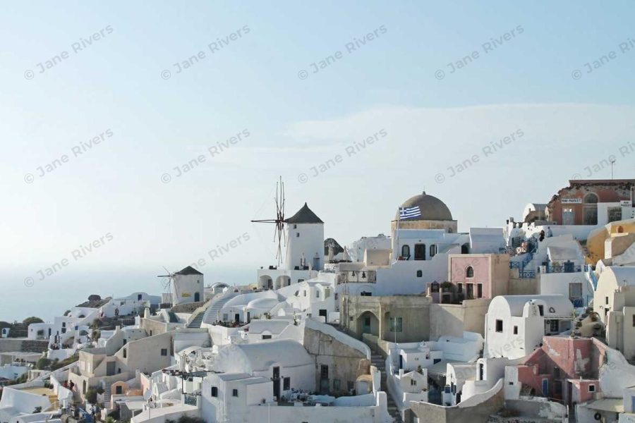 A white Greek village under a pale sky with a barely visible tiled watermark at 10% opacity