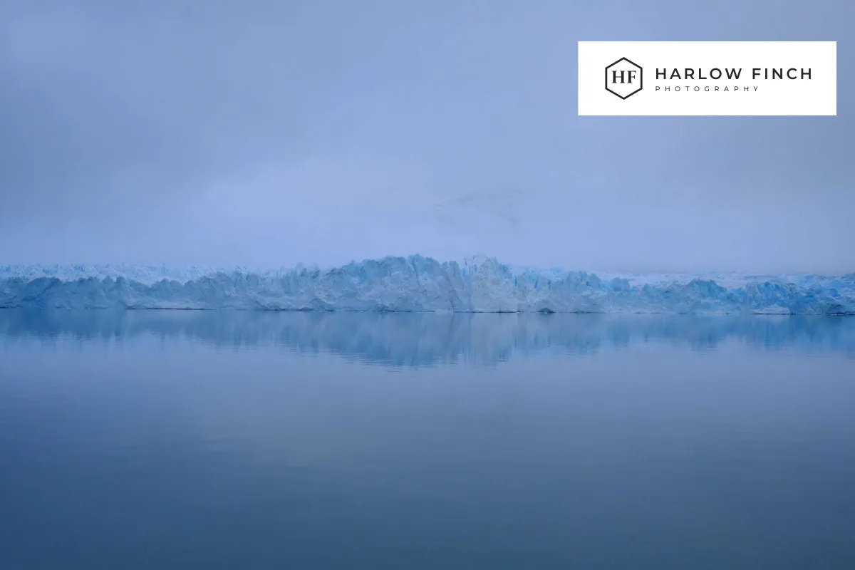 A misty glacier lake with a dark Harlow Finch Photography logo sitting inside a solid white rectangle in the upper right