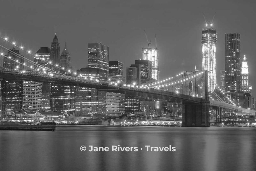 A black and white night skyline with a white watermark on the dark water