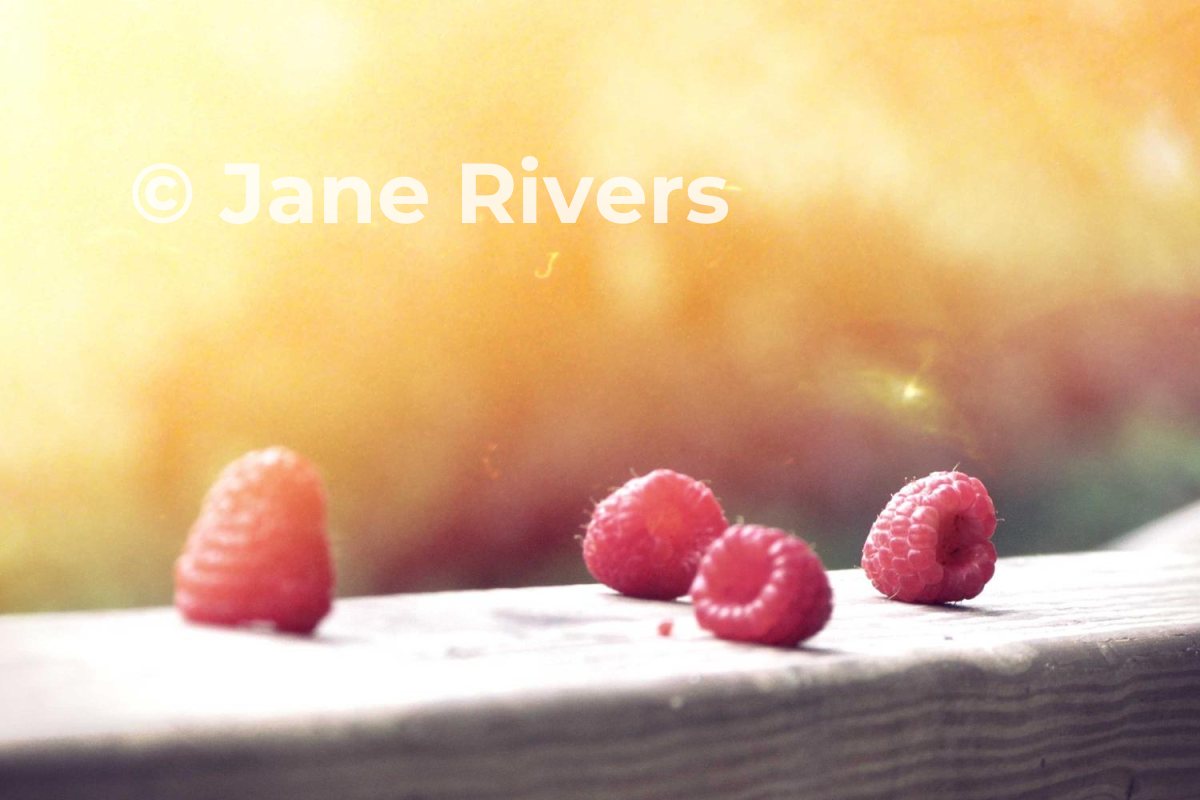 A bright, washed-out photo of raspberries with a white watermark that nearly disappears