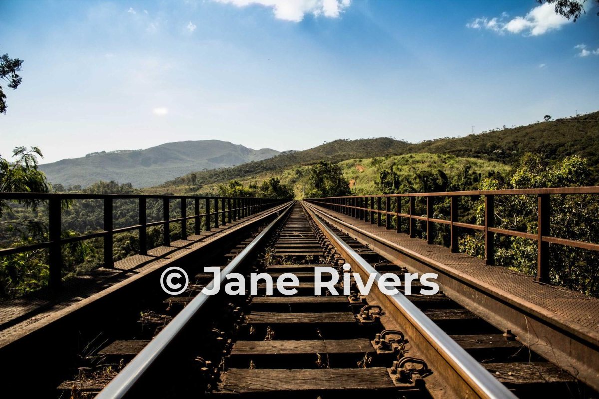 A railway bridge running into green hills with a white Jane Rivers watermark and a soft shadow