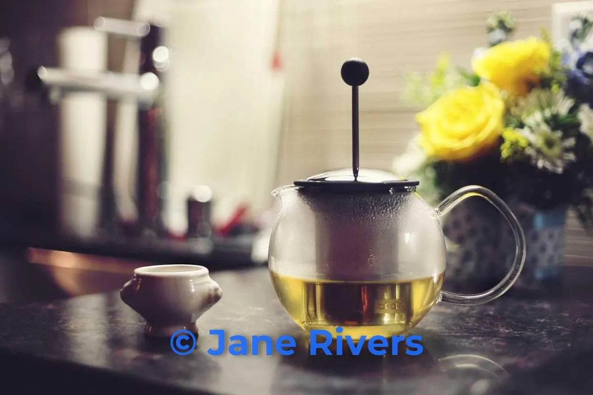 A warm photo of a glass teapot and yellow flowers with a bright blue watermark that clashes