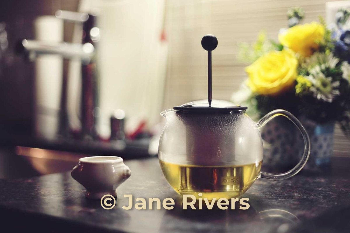 The same teapot photo with a warm cream watermark that matches the light in the photo