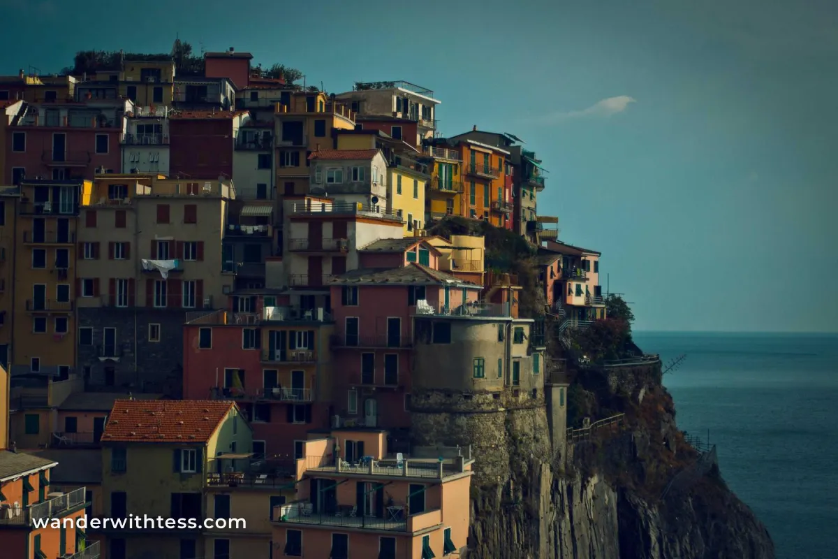 Colorful cliffside houses above the sea at dusk with wanderwithtess.com in white text in the lower left corner