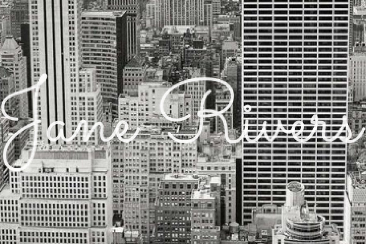 A close-up of a thin script watermark over city buildings, with most of the buildings visible between the strokes