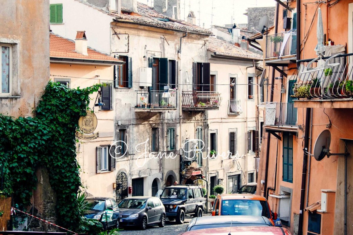 A busy Italian street with a thin script watermark that is almost impossible to read