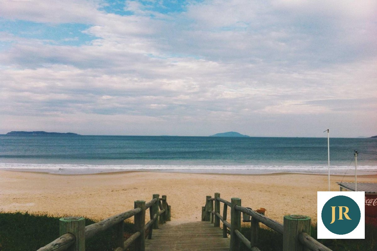 A beach boardwalk with a round logo inside a solid white square in the corner