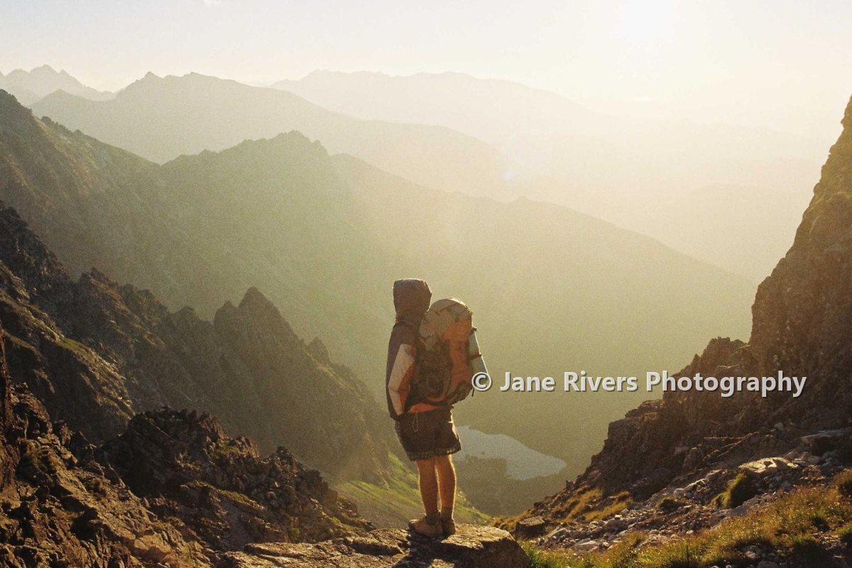 A photo of a hiker in the mountains with a watermark beside the hiker on the lower third