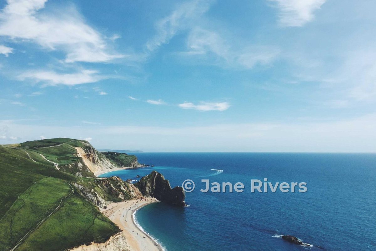 A green headland and blue sea with a watermark over the water about a third of the photo wide