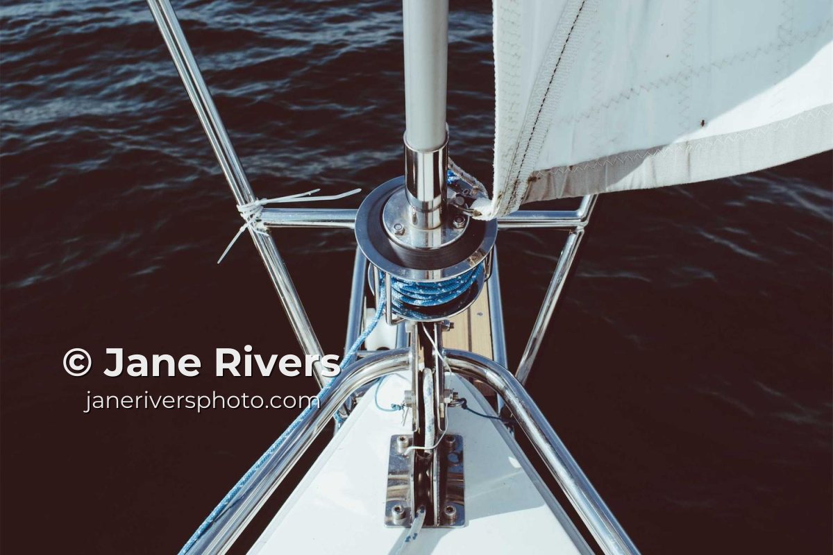 The bow of a sailboat over dark water with the watermark © Jane Rivers and a web address underneath