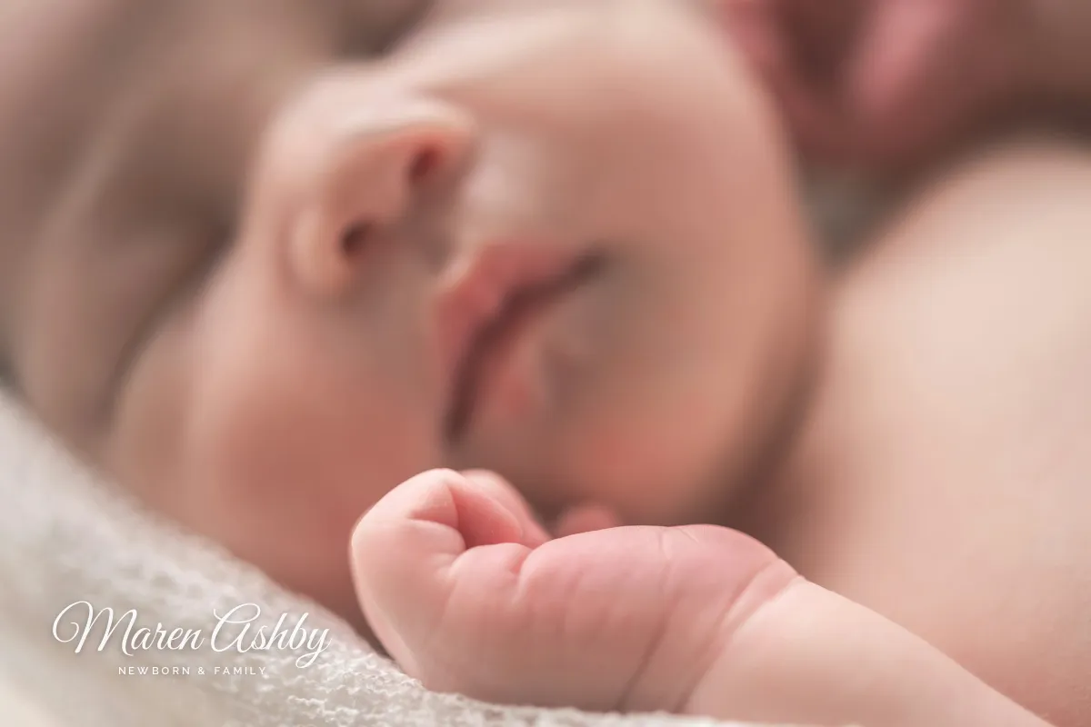 The same sleeping newborn with a small white signature and NEWBORN & FAMILY on the blanket in the lower left corner