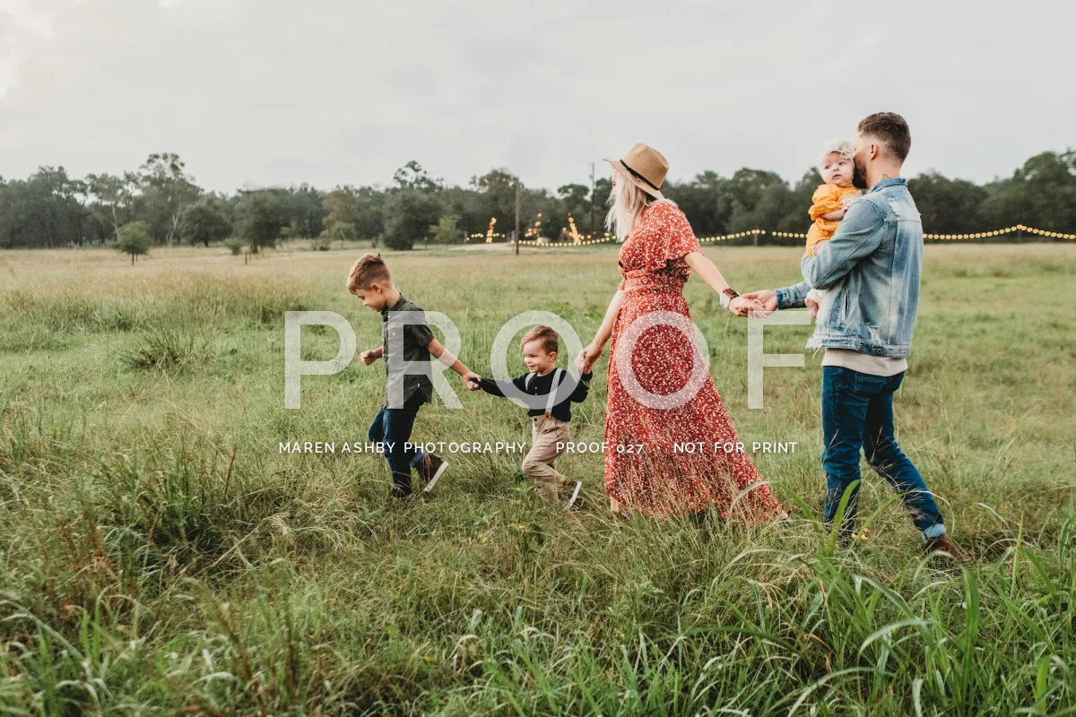 A family of five walking hand in hand through a meadow, with a large faint PROOF across the middle and MAREN ASHBY PHOTOGRAPHY, PROOF 027, NOT FOR PRINT in small capitals beneath it