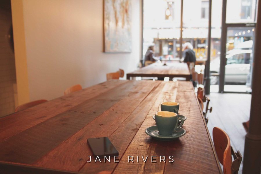A long wooden table set by a window with JANE RIVERS in small, widely spaced capitals
